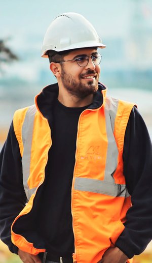 Ouvrier du bâtiment souriant avec un casque et un gilet de sécurité